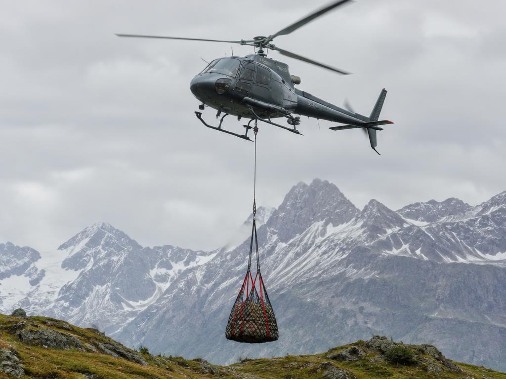 Hubschrauber transportiert ein Lastnetz im Gebirge